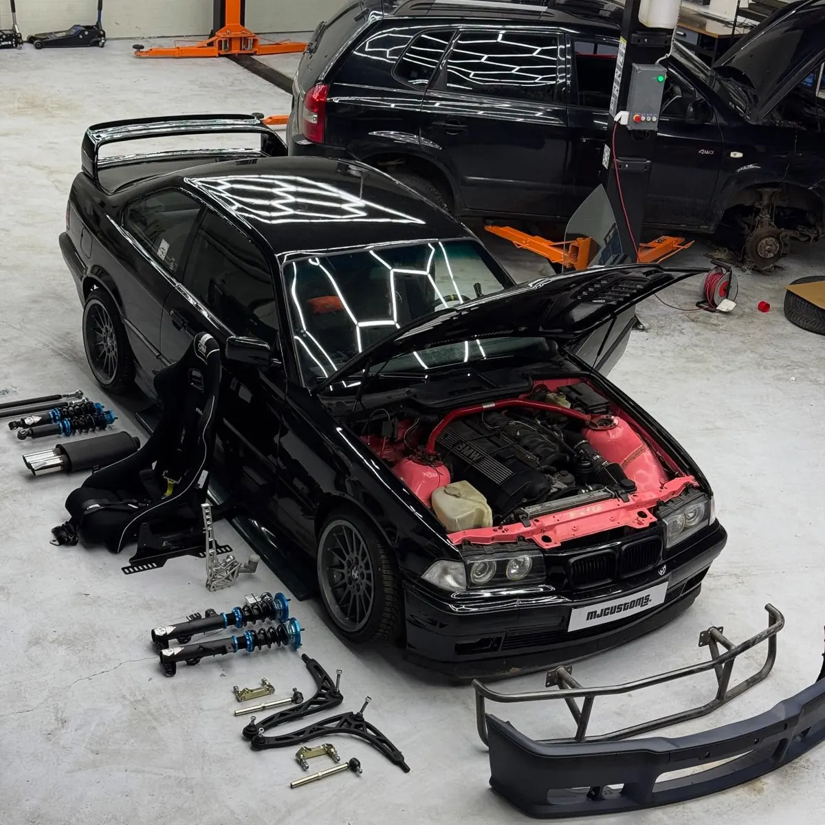 E36 v dielni MJcustoms s otvorenou kapotou, okolo nové tlmiče, ramená a sedačka OMP